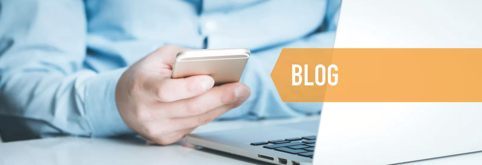 Stockfoto Mann mit Handy und Notebook am Schreibtisch. Von rechts eingeblendet Schriftzug "Blog".